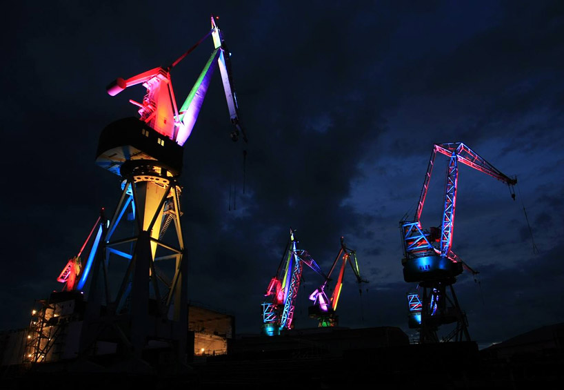 skira's illuminated shipyard cranes look like orgami in the sky