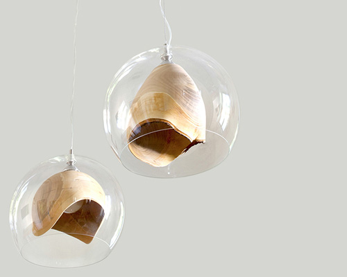 elegant teca lamp combines raw woodturning with glass enclosure