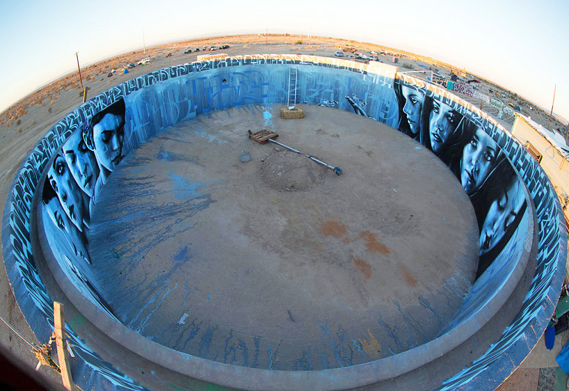 artists paint circular mural inside abandoned water tank in the desert