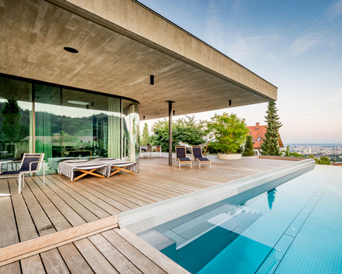 caramel architects' poolside family home overlooks city in austria