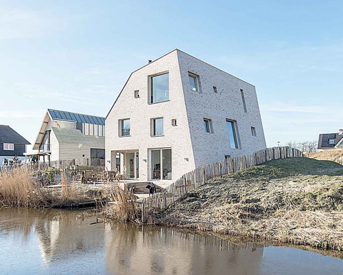 global architects' asymmetric rock house emerges from dune landscape in holland