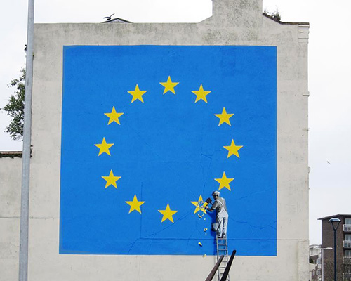 banksy takes on brexit: mural shows metalworker chipping away at the EU flag