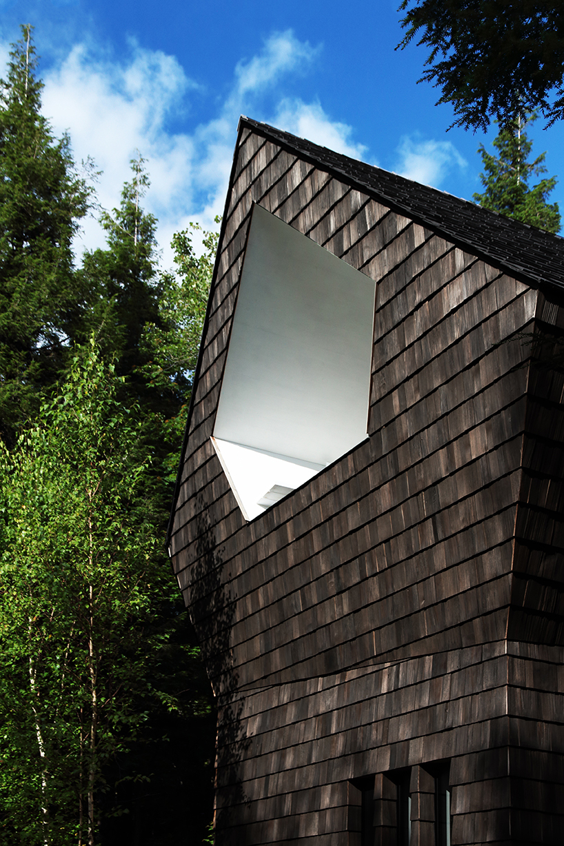 bird hut house by YH2 emerges from the trees in canadian forest