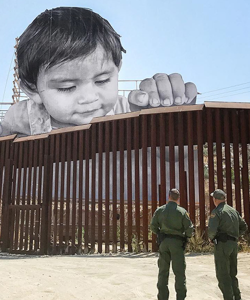 child curiously peeks over the US-mexico border in JR's installation on immigration
