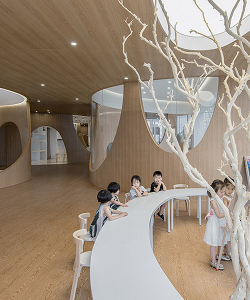 archstudio's children's art school features multiple ranges of artificial wood-clad hills