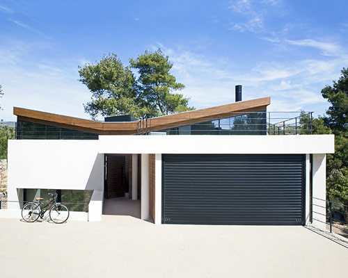 butterfly-roof 'wedge house' by schema is located in a piny area in greece