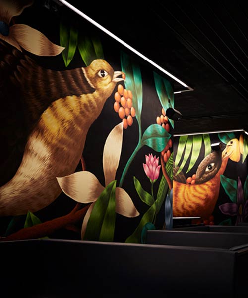 giant hand-painted murals depict tropical birds at this viennese cocktail bar by tzou lubroth architekten