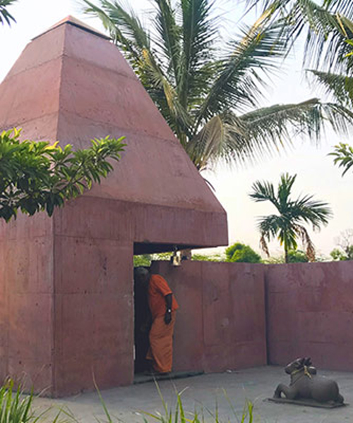 karan darda's orange hindu temple in india creates a contrast with green surroundings