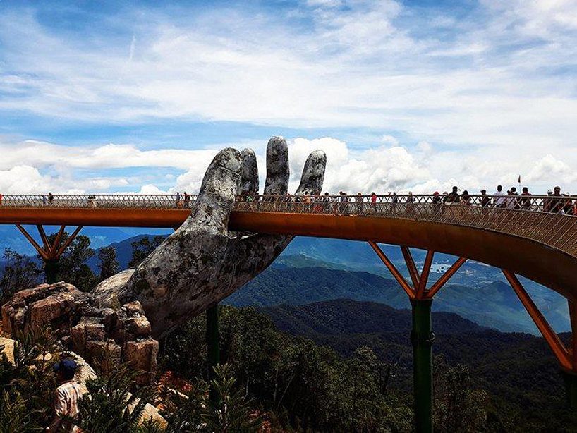 a giant pair of hands lifts vietnam's da nang golden bridge into the sky