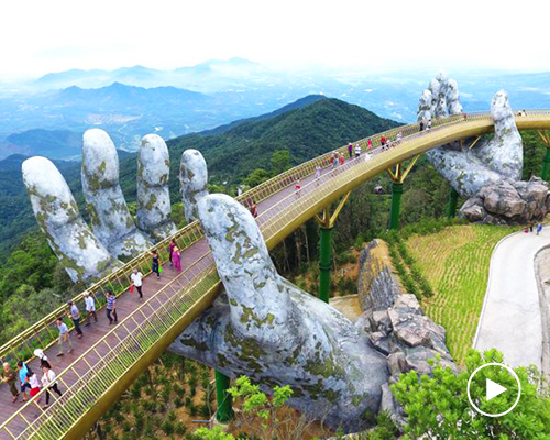 a giant pair of hands lift vietnam's da nang golden bridge into the sky