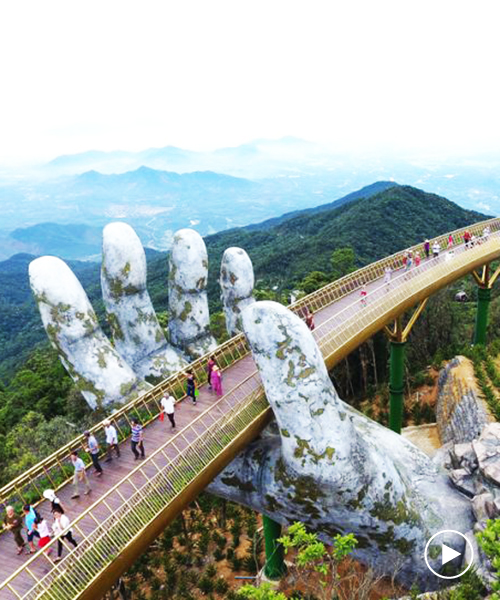 a giant pair of hands lift vietnam's da nang golden bridge into the sky