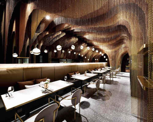 gold chains hanging from the ceiling of this tea house mimic the shape of chinese hills