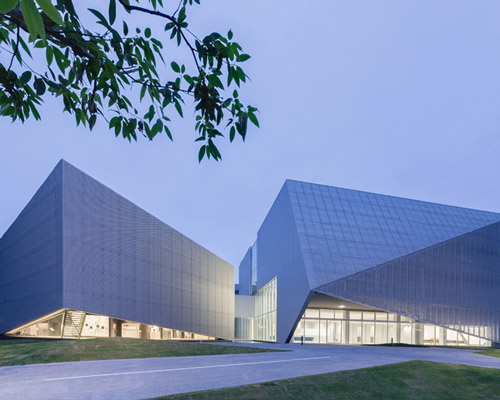 this transparent showroom in japan is surrounded by an artificial pond