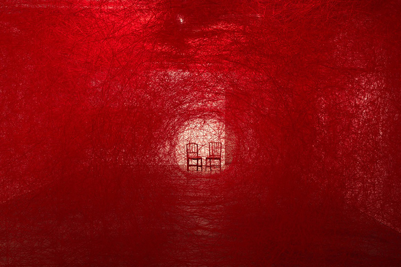 chiharu shiota weaves webs around two seated performers, 100 years after WWI