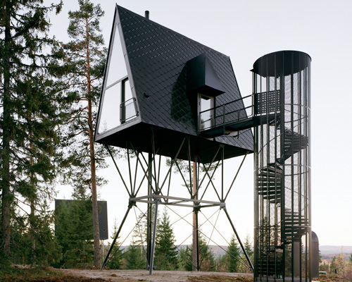 all-black stilted cabins by espen surnevik are elevated among the trees