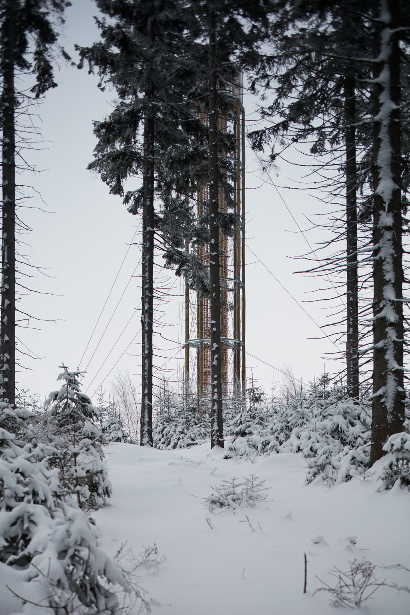 a timber lookout tower rises above the forested mountains of a czech ski area