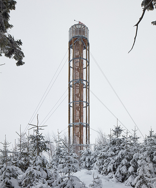 a timber lookout tower rises above the forested mountains of a czech ski area