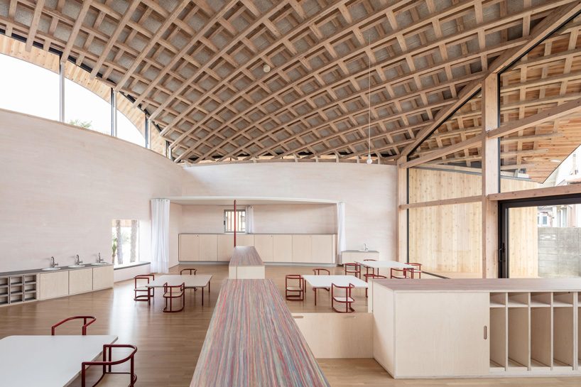 curved wood lattice roof hangs above nasca's blue sky nursery school in japan