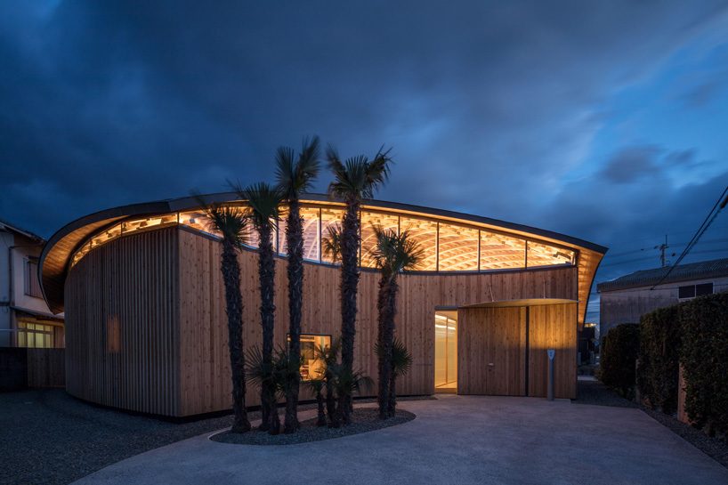 curved wood lattice roof hangs above nasca's blue sky nursery school in japan