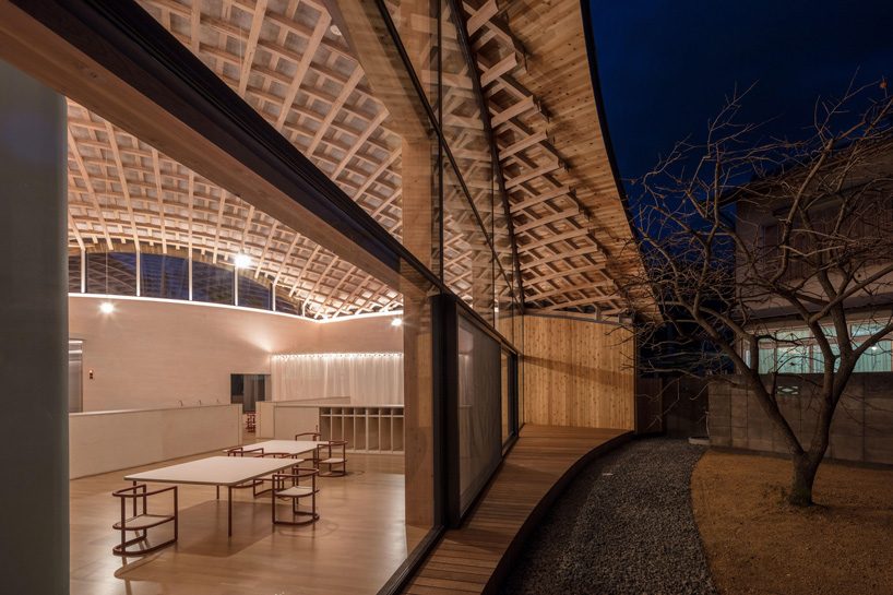 curved wood lattice roof hangs above nasca's blue sky nursery school in japan
