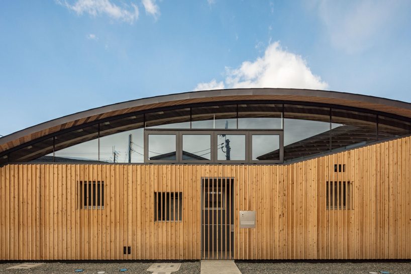 curved wood lattice roof hangs above nasca's blue sky nursery school in japan