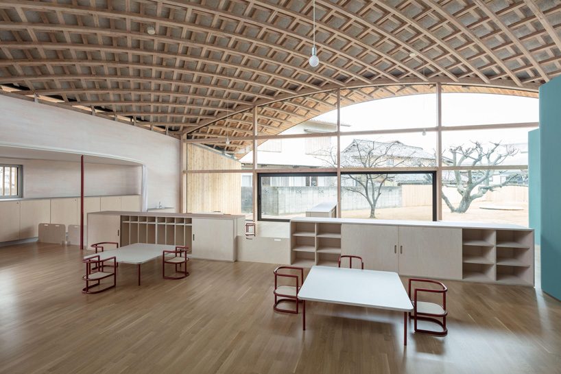 curved wood lattice roof hangs above nasca's blue sky nursery school in japan