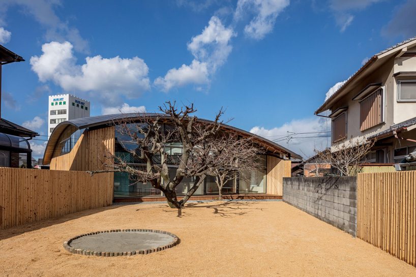curved wood lattice roof hangs above nasca's blue sky nursery school in japan