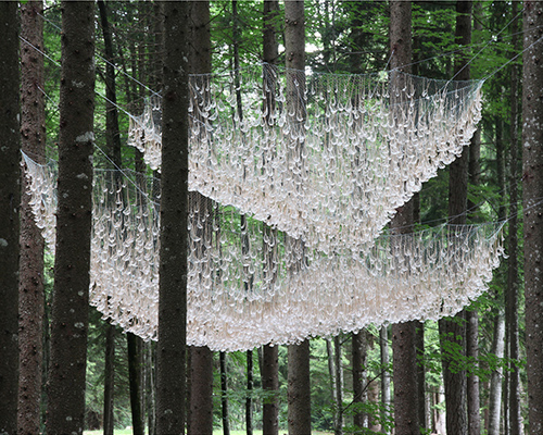 suspended among the trees, rainwater collecting sculptures mimic elaborate chandeliers