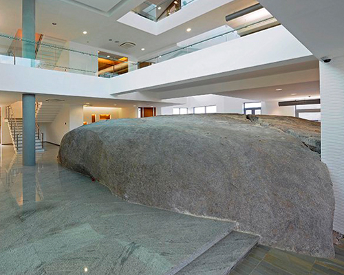 pentaspace wraps an office around a massive granite boulder in india