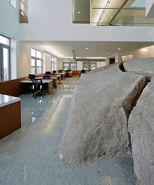 pentaspace wraps an office around a massive granite boulder in india