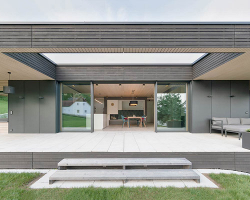 superfuturegroup surrounds floating wooden bungalow with wide veranda in austria