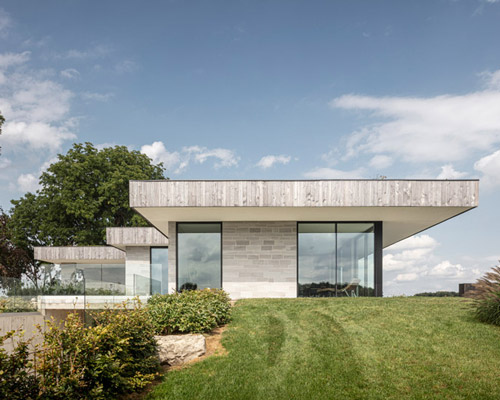 chris collaris architects designs villa with locally-sourced materials amidst meadow in canada