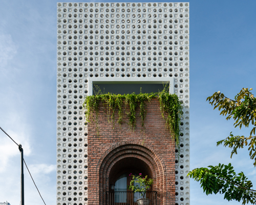 cội design inserts arched brick balcony to the perforated façade of this house in vietnam