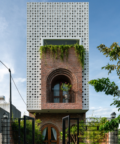 cội design inserts arched brick balcony to the perforated façade of this house in vietnam