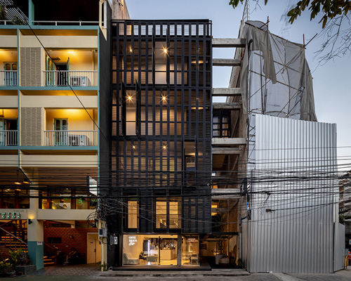 IDIN architects completes pa prank hostel in bangkok with façade of black shutters