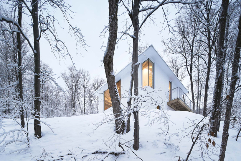 naturehumaine sets monochrome 'poisson blanc' cabin within forest in canada
