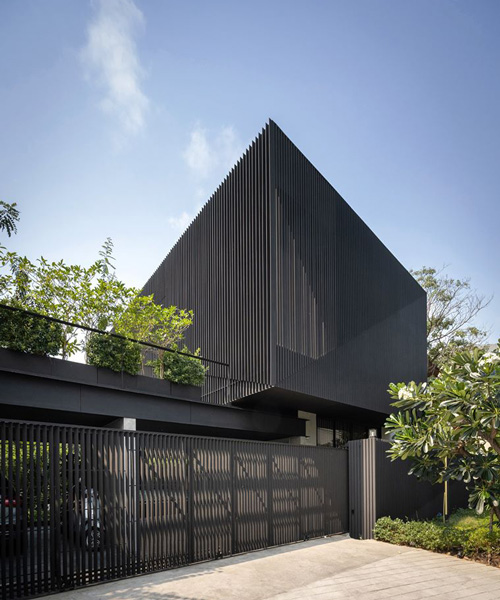 octane's k krit residence in bangkok is clad in façade of black unequal steel battens