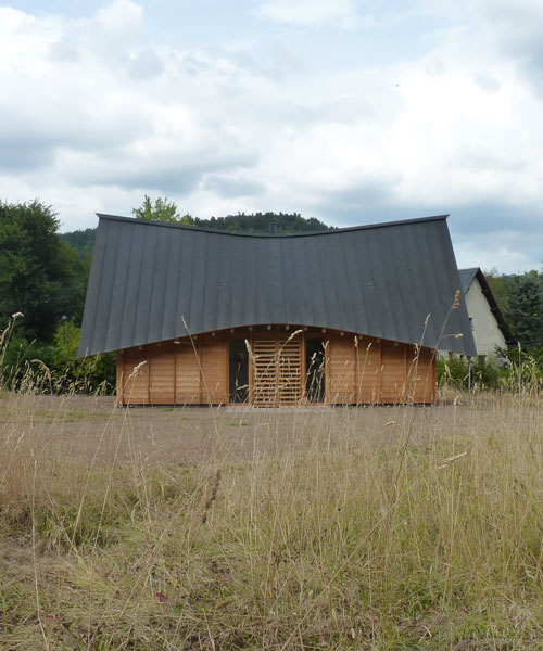a curved roof tops this wooden house designed by arba in rural france