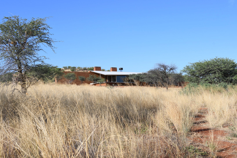 slee & co. architects' red earth hunting lodge emerges from the namibian landscape