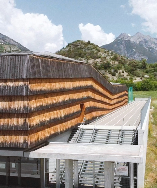 larch cladding folds over a gymnasium in france to echo the mountain topography