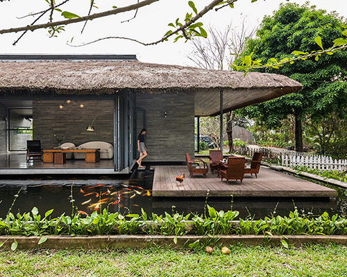 house with thatched roof settles next to peaceful pond in vietnam