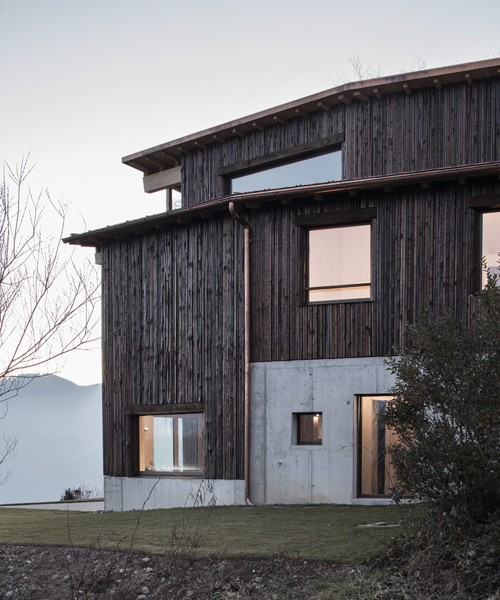 atelier risi combines tree bark + concrete for the exterior of this house in böschi, switzerland