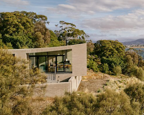 this coastal house by topology studio nestles into the landscape of otago bay in tasmania