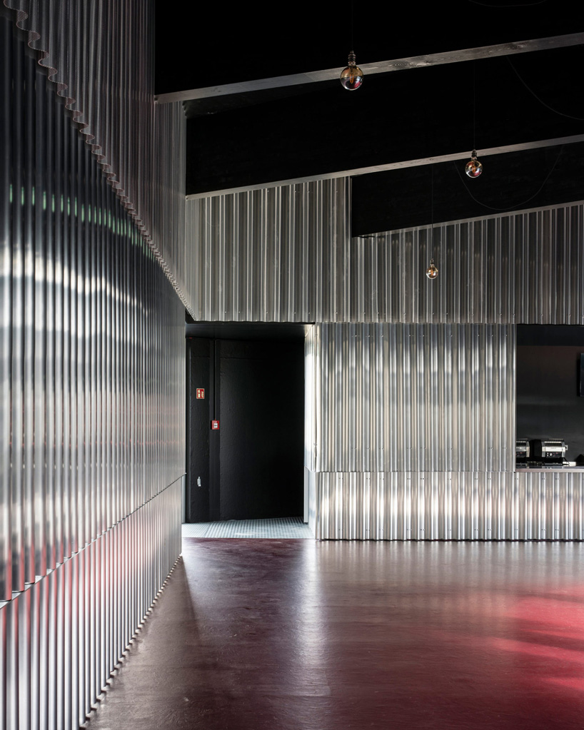black lacquered timber structure with aluminum walls and red flooring in carmody groarke's circular aluminum pavilion
