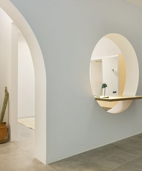 sculptural partition wall with curved openings organizes apartment interior in athens, greece
