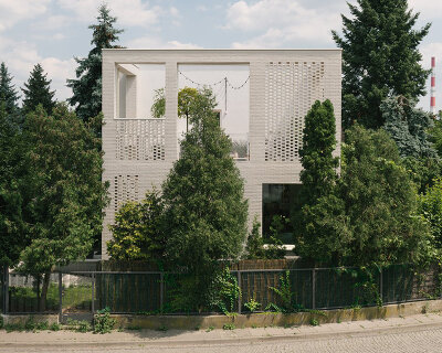 MFRMGR architects adds perforated white-brick frame to 1970s terrace house in poland