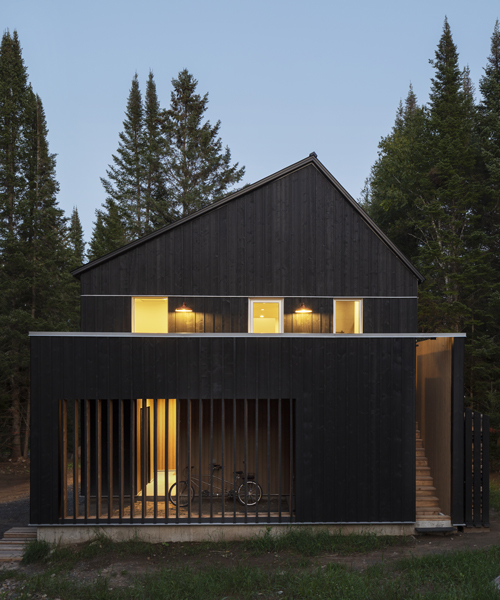 blackened timber helps blend 'B+L residence' into a tree-covered site in quebec