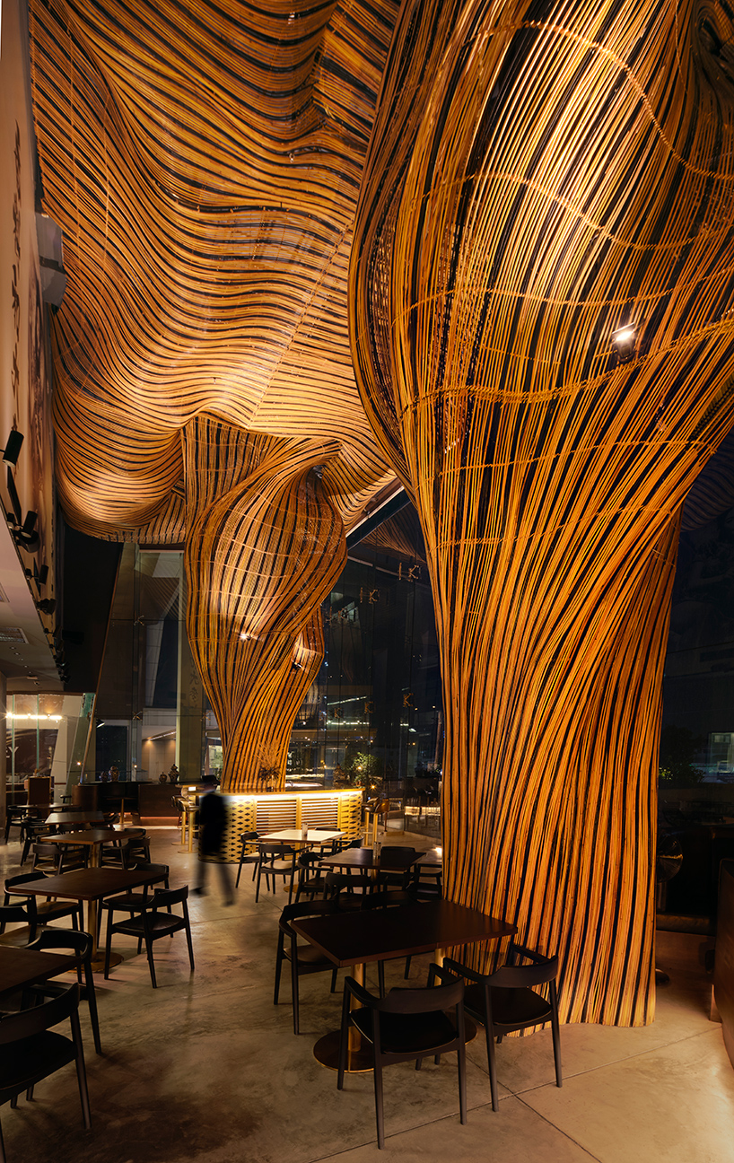 billowing rattan columns by enter projects occupy bangkok's spice & barley interior