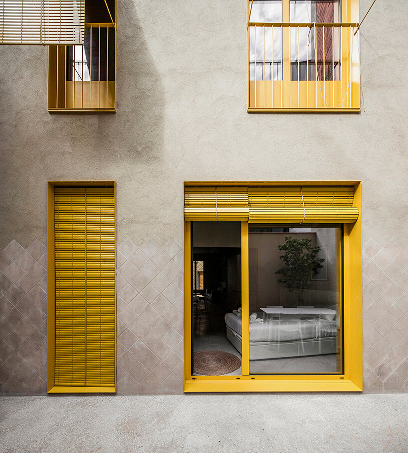 anna & eugeni bach punctuate 'seven lives' building in barcelona with yellow façade elements