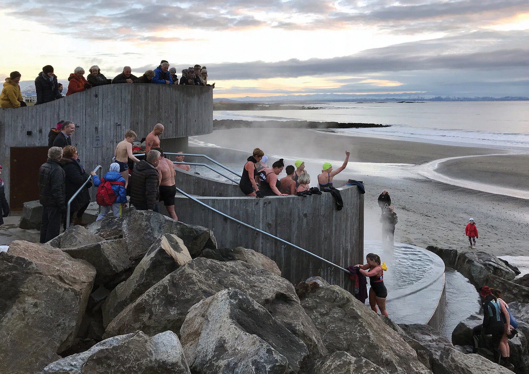basalt architects nestles 'guðlaug baths' into a rocky breakwater barrier in iceland